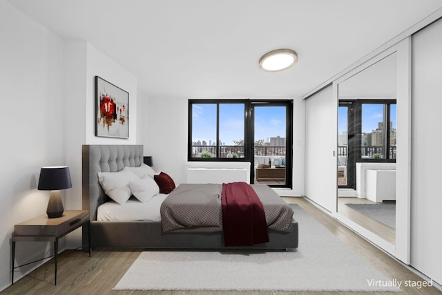 bedroom featuring a city view, access to outside, and wood finished floors