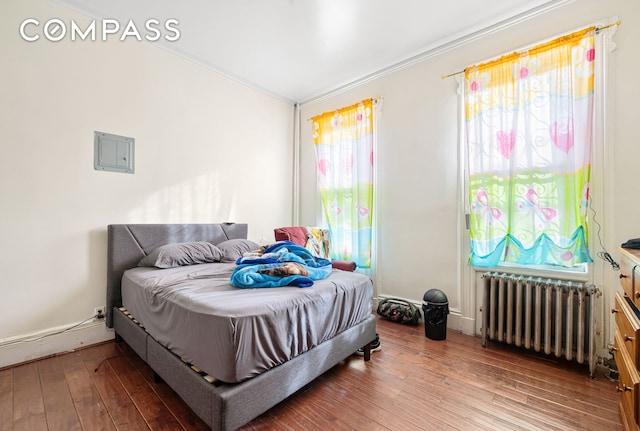 bedroom with ornamental molding, radiator heating unit, and hardwood / wood-style flooring