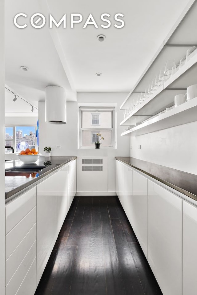 kitchen with dark wood-type flooring, modern cabinets, a sink, open shelves, and white cabinets