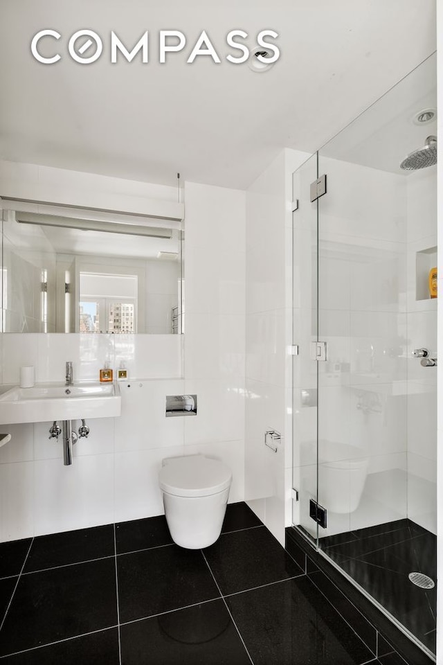 full bathroom with toilet, a stall shower, tile patterned floors, tile walls, and a sink