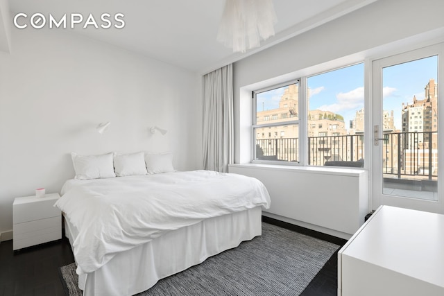 bedroom featuring a city view, dark wood-style floors, and access to outside