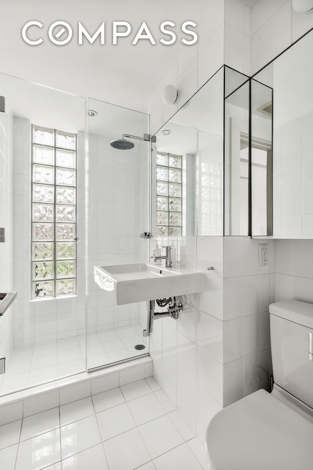 bathroom featuring toilet, tile walls, a stall shower, and tile patterned flooring