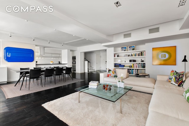 living area with track lighting, visible vents, built in features, stairs, and wood finished floors