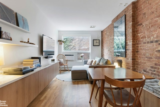 dining room featuring baseboard heating, light wood-style floors, and brick wall