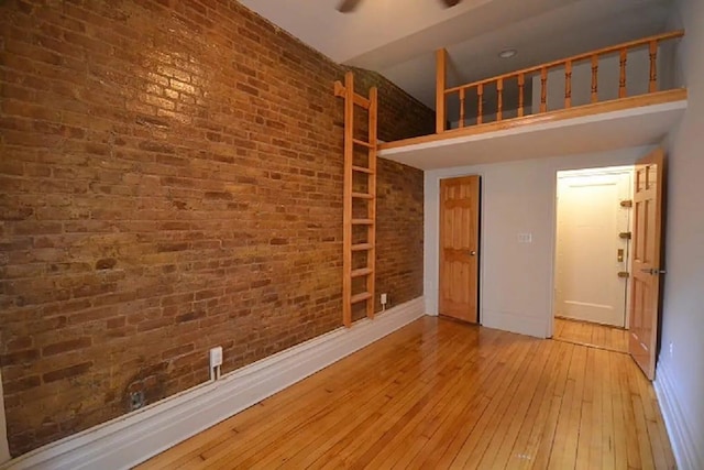 346 W 87th St, New York City, NY 10024 - unfurnished room featuring brick wall, hardwood / wood-style floors, baseboards, and a towering ceiling