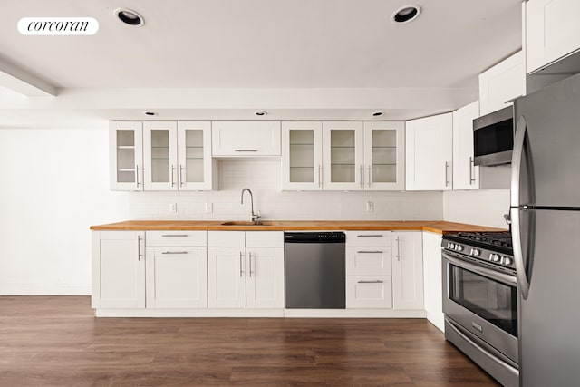 kitchen with butcher block counters, appliances with stainless steel finishes, a sink, decorative backsplash, and recessed lighting