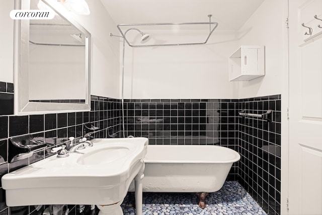 bathroom with tile walls, a freestanding tub, wainscoting, and tile patterned floors
