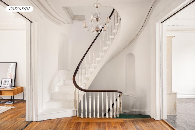 staircase with visible vents, an inviting chandelier, and hardwood / wood-style flooring