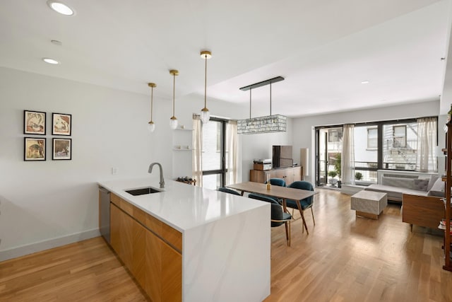 kitchen with a sink, a peninsula, healthy amount of natural light, light wood-style floors, and recessed lighting