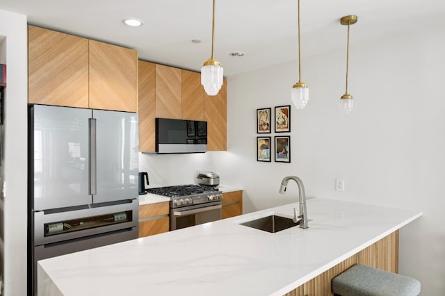 kitchen with stainless steel range with gas stovetop, a sink, freestanding refrigerator, modern cabinets, and light stone countertops