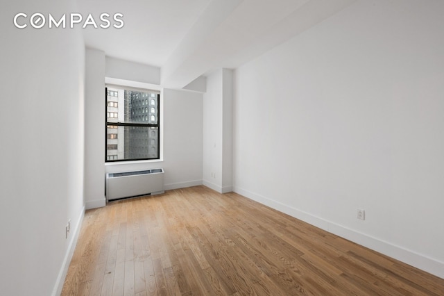 unfurnished room with radiator, wood finished floors, and baseboards