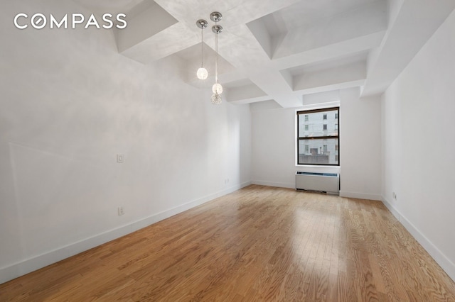 empty room with beam ceiling, coffered ceiling, baseboards, and wood finished floors