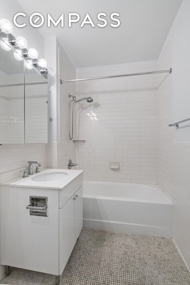 bathroom featuring tile patterned flooring, tasteful backsplash, vanity, shower / bath combination, and tile walls