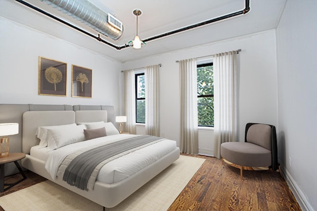 bedroom with visible vents, baseboards, and wood finished floors