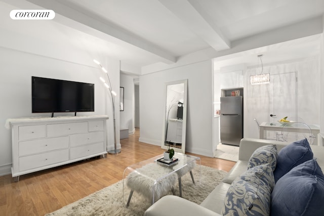 living area featuring visible vents, beam ceiling, baseboards, and light wood finished floors