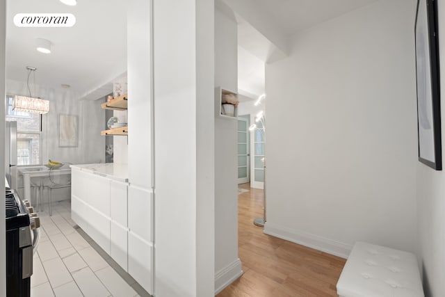 hallway featuring visible vents, light wood-style flooring, and baseboards