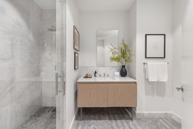 full bath featuring vanity, a shower stall, baseboards, and backsplash