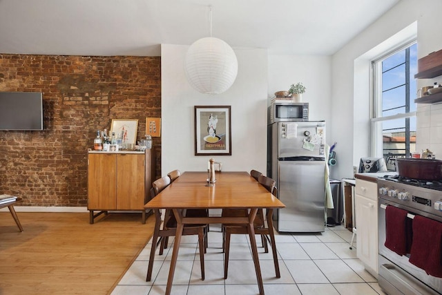 dining area featuring light wood-style flooring and brick wall