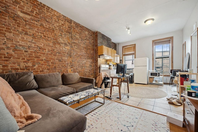 living area with light tile patterned flooring, brick wall, and washer / clothes dryer