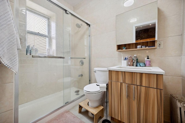 full bathroom featuring toilet, tile walls, radiator heating unit, and a stall shower