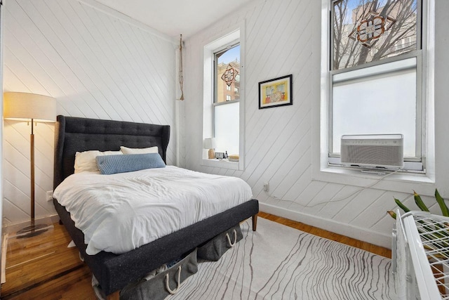 bedroom with cooling unit, wood finished floors, and baseboards