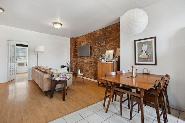 dining room featuring light wood-style flooring and brick wall