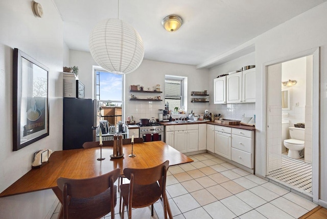 kitchen with open shelves, white cabinets, light tile patterned flooring, and stainless steel appliances