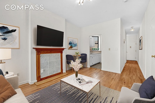 living room featuring light wood-type flooring, baseboards, and a tile fireplace