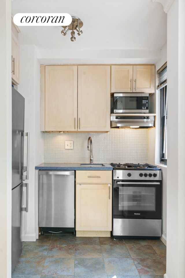 kitchen with light brown cabinets, a sink, tasteful backsplash, ventilation hood, and stainless steel appliances