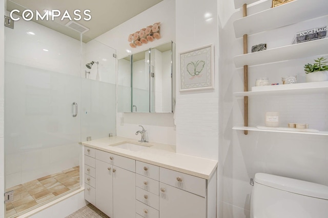 bathroom featuring visible vents, toilet, a stall shower, and vanity