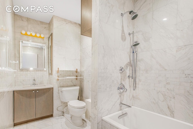 bathroom featuring toilet, marble finish floor, shower / bathing tub combination, tile walls, and vanity