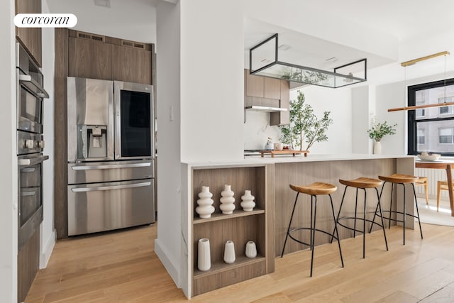 kitchen with stainless steel appliances, light wood-style floors, modern cabinets, and a breakfast bar