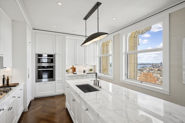 kitchen featuring decorative backsplash, white cabinetry, stainless steel appliances, and a sink