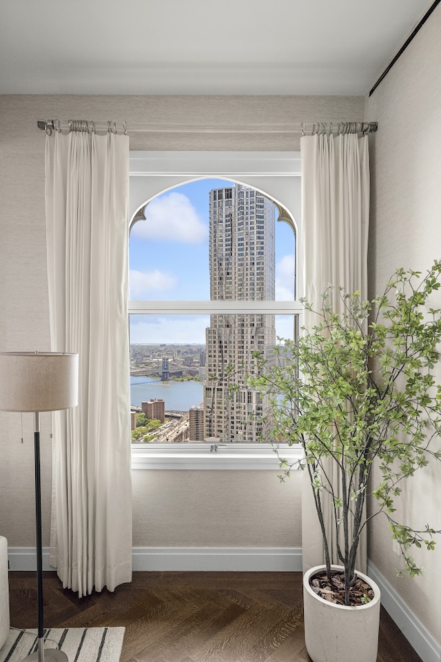 interior space featuring baseboards, a water view, and a view of city