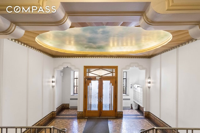 foyer entrance with radiator heating unit, french doors, a raised ceiling, and baseboards