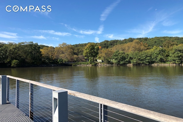 view of dock with a water view and a forest view