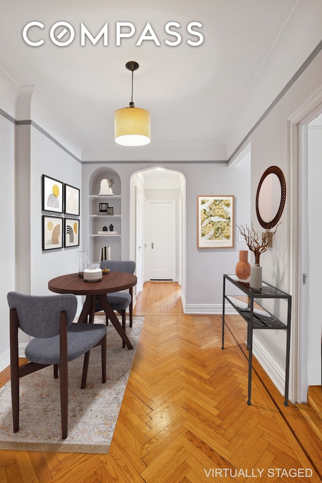 dining space with built in features, baseboards, arched walkways, and ornamental molding