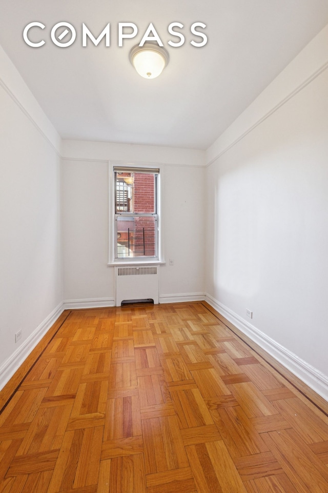 unfurnished room featuring radiator heating unit and baseboards