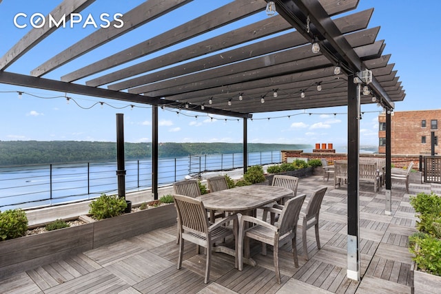 wooden terrace with a pergola, outdoor dining area, and a water view