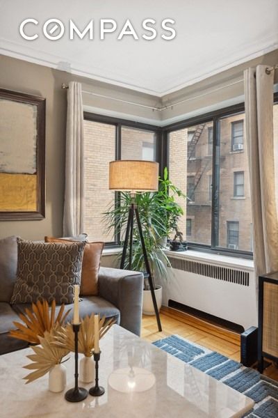 sitting room with wood finished floors, plenty of natural light, radiator, and ornamental molding