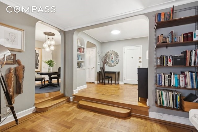 interior space featuring baseboards, arched walkways, an inviting chandelier, and crown molding