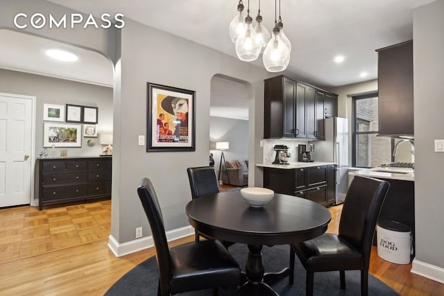 dining space with recessed lighting, parquet floors, baseboards, and arched walkways