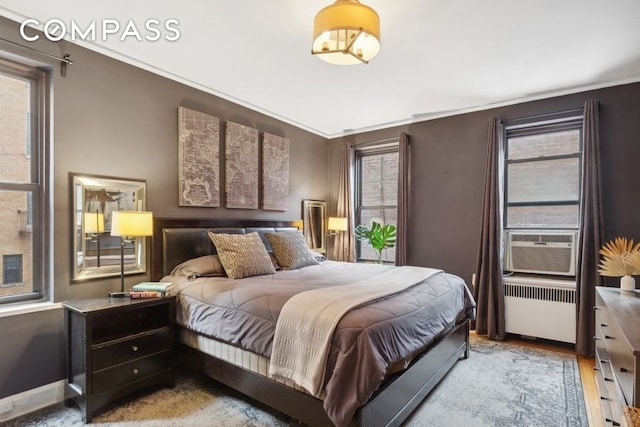 bedroom featuring radiator, baseboards, ornamental molding, cooling unit, and wood finished floors