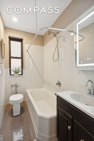 bathroom featuring vanity, tile patterned flooring, shower / bath combination, tile walls, and toilet