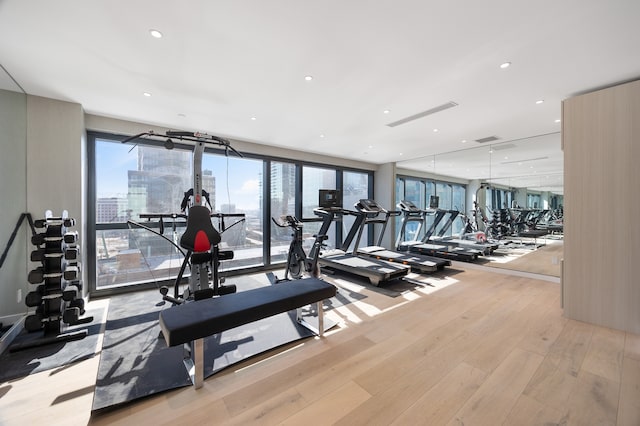 workout area featuring recessed lighting, a view of city, and light wood-style flooring