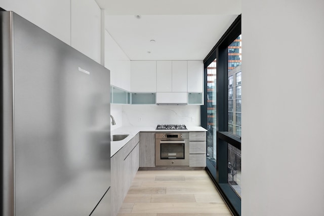 kitchen with modern cabinets, open shelves, a sink, appliances with stainless steel finishes, and light countertops