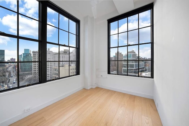 empty room with baseboards, a view of city, and wood finished floors