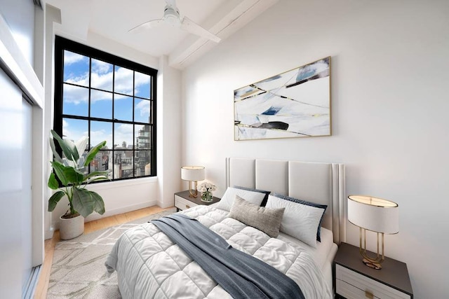 bedroom with beam ceiling, wood finished floors, and a ceiling fan