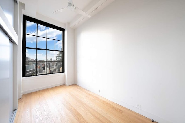 spare room featuring a ceiling fan, beamed ceiling, wood finished floors, and baseboards