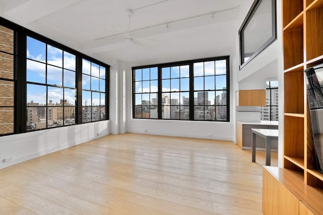 unfurnished sunroom featuring a city view, a healthy amount of sunlight, track lighting, and ceiling fan